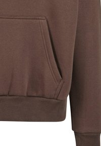 Brun sweatshirt med en frontlomme, ribbet manchetter og kant. Blød tekstur og diskret syning langs sømmene.