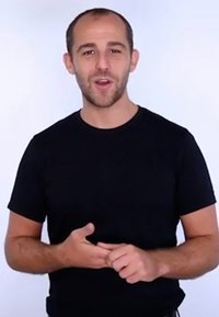 Zwarte t-shirt met korte mouwen op een persoon met kort, lichtbruin haar, staande tegen een effen witte achtergrond, gebarend met zijn handen.