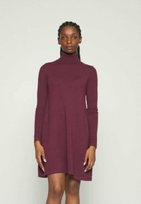 Φόρεμα με ψηλό γιακά σε σκούρο μπορντό, από μαλακό πλεκτό ύφασμα. Διαθέτει μακριά μανίκια και φαρδιά κρόσσια, με χαλαρή γραμμή.