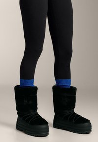 Stivali neri foderati in pelliccia con finitura testurizzata, dotati di suola resistente e lacci neri; completati da scaldamuscoli a coste blu sopra.