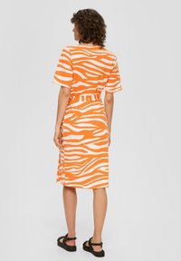 Orange-weiß gestreides Kleid mit kurzen Ärmeln und taillierter Taille, mit einem lässigen Schnitt und seitlichem Schlitz, aus weichem Stoff gefertigt.