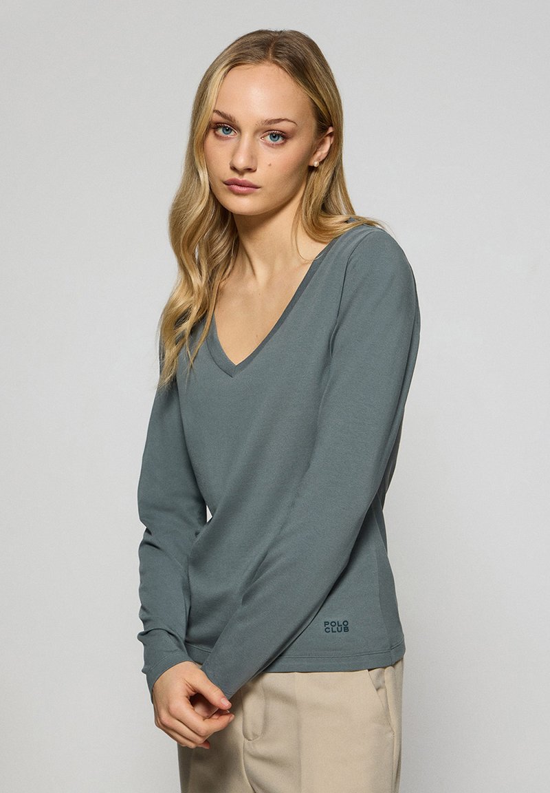 V-hals långärmad skjorta i gråslate bomullsblandning, med avslappnad passform och subtil logotypdetalj vid sidokanten.