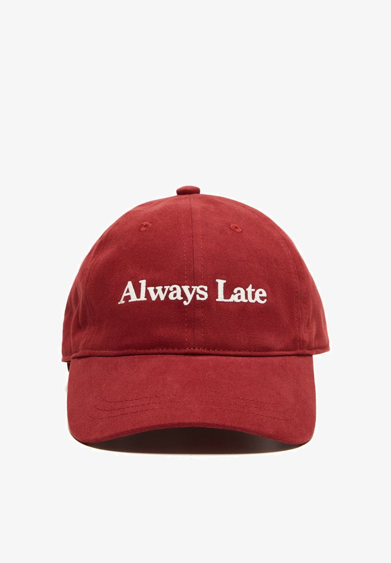 Casquette de baseball rouge avec texte brodé blanc "Always Late" sur le devant, présentée sur fond blanc.
