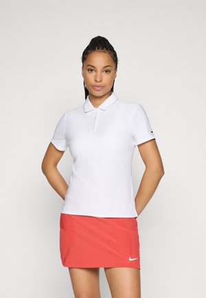 White polo shirt with a collar and short sleeves, paired with a red skirt featuring a textured pattern and a Nike logo on the front.