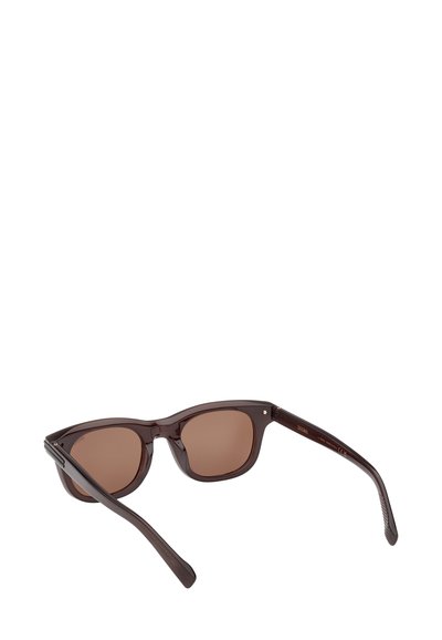 Brązowe plastikowe okulary przeciwsłoneczne o kwadratowych oprawkach, brązowych przyciemnianych soczewkach i strukturalnych zausznikach. Z metalowymi ozdobami przy zawiasach dla zwiększenia trwałości.