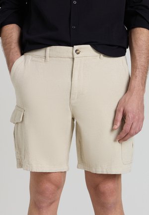 Pantaloni cargo beige con un tessuto strutturato, tasche frontali e una tasca laterale con patta. Chiusura con bottone in vita.