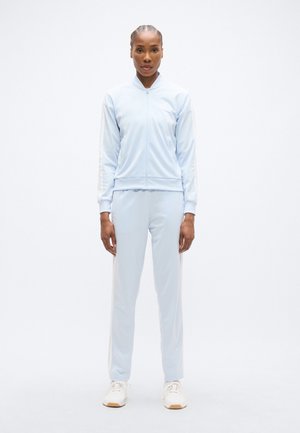 Ανοιχτό μπλε φόρμα με μπουφάν με φερμουάρ και παντελόνι που ταιριάζει. Διαθέτει λευκές πλευρικές ρίγες και μαλακό, ελαστικό υλικό.