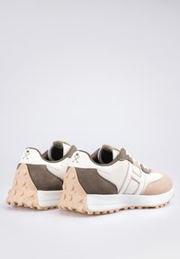 Calzado con una combinación de ante beige y malla crema, que cuenta con una suela acolchada, acentos de goma redondeados y elementos de diseño en contraste.