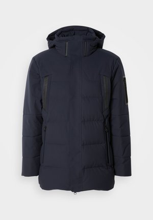 Navy pufferjack met een capuchon, voorzien van zwarte accenten, ritsen en twee zijzakken. Het materiaal lijkt glad met gestikte segmenten.