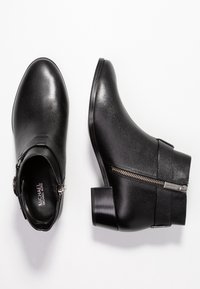 Schwarze Lederstiefeletten mit strukturierter Oberfläche, runder Zehenform, kurzem Blockabsatz, seitlichem Reißverschluss und Schnallen-Detail am Knöchelriemen.