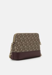 Brązowa torebka w wzory z bordową podstawą, złotymi okuciami i łańcuszkiem na ramię. Posiada zamek błyskawiczny i teksturowaną tkaninę.