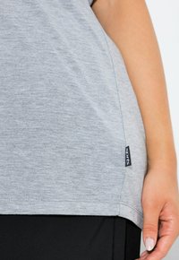 Graues kurzärmeliges T-Shirt aus weichem, strukturiertem Stoff mit einem unteren Saum und einem kleinen schwarzen Etikett an der Seite mit der Aufschrift "sports".