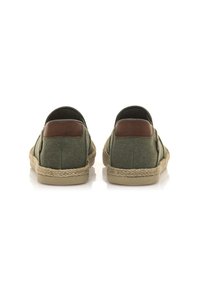 Baskets slip-on en toile verte avec une finition texturée, accents en cuir brun et semelles en jute tressé. Détails de coutures subtils sur les côtés.