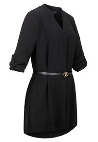 Robe tunique noire à manches longues avec manches retroussées et une fine ceinture noire avec deux anneaux dorés entrelacés à la taille.