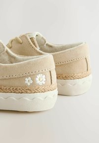 Chaussures en toile beige avec broderie florale blanche, semelle texturée et garniture en jute. Bout rond et design bas.