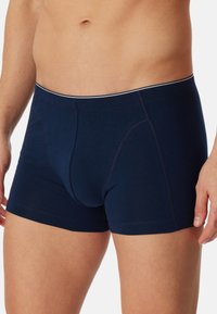 Marineblauwe boxershorts gemaakt van een zachte, rekbare stof met een contrasterende witte tailleband en eenvoudige naaddetaille. 
