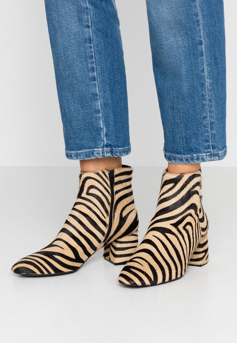 Bottines à bout pointu avec imprimé zèbre beige et noir, dotées d'une finition texturée, d'un talon épais et d'une fermeture éclair latérale.