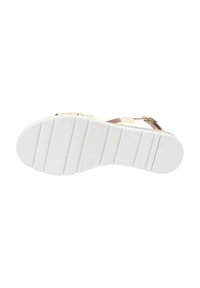 Suola di sandali bianchi con un grip testurizzato, che mostra scanalature orizzontali e un bordo liscio. Cinghie beige chiaro con una fibbia in metallo.