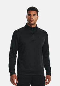 Pullover nero a maniche lunghe realizzato in un tessuto morbido e elastico. Presenta un colletto alto e una mezza zip, con un piccolo logo sul fronte.