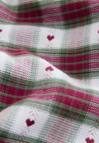 Bomullstyg med ett rött och grönt rutmönster med hjärtmotiv, mjuk textur och växelvis vita rutor.