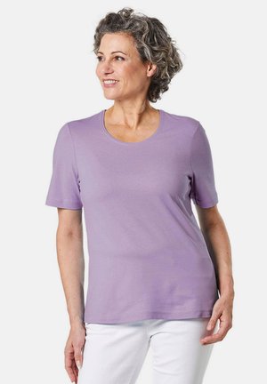 Lila Kurzarm-T-Shirt mit rundem Ausschnitt, aus weichem Stoff, mit lockerem Schnitt und glatter Textur. Getragen mit weißen Hosen.