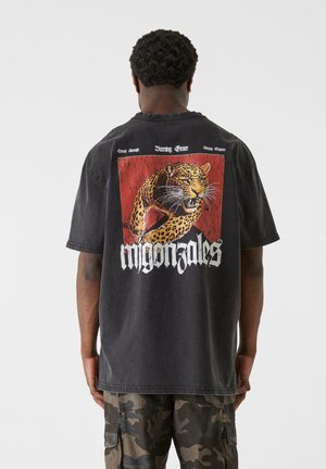 Sort oversized t-shirt med et leopardgrafik og fed tekst på ryggen. Har rund halsudskæring og korte ærmer.