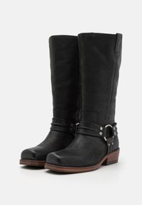 Black leather knee-high boots with a rounded toe, silver hardware accents, and a brown stacked heel. Features a decorative strap detail.