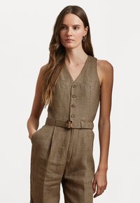 Combinaison à carreaux beiges avec un décolleté en V, des boutons à l'avant, une taille ceinturée et des poches latérales. La texture est lisse avec une coupe classique ajustée.