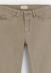 Vaqueros de denim beige con un diseño clásico de cinco bolsillos, cremallera central y cierre de botón. La tela tiene una textura suave con un desgaste mínimo.