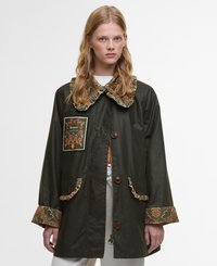 Green fabric jacket featuring a floral-patterned collar, a decorative patch, and ruffled accents on pockets and sleeve cuffs.
