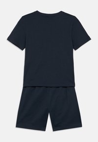 Tumesinise lühikeste varrukatega T-särk ja sobivad lühikesed püksid pehmest kangast, lõdva istuvusega. Riietusel on lihtne ühevärviline disain.