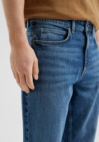 Sinised denim teksad klassikalise lõikega, keskmise tõusuga talje, viie tasku disain ja õrn hääbumine jalgadel.