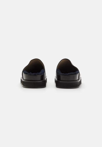 Fekete slip-on cipők sima bőr külsővel, puha sötétkék belsővel és vastag fekete talppal. Lekerekített hátsó kialakítás.
