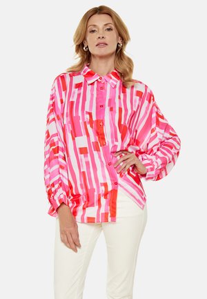 Langarm button-up shirt met een levendig roze en rode geometrische print. Gemaakt van zachte stof met een klassieke kraag en een oversized pasvorm.