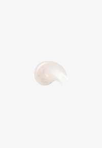 Lys beige kremklatt med blank tekstur og små bobler, isolert på hvit bakgrunn.
