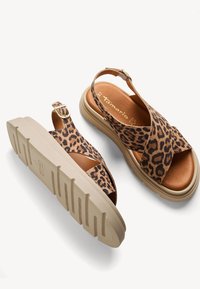 Sandal con stampa leopardata, con cinturini incrociati, plantare in pelle marrone, suola imbottita e cinturino alla caviglia regolabile con finiture dorate.