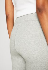 Leggings grises hechos de un material suave y elástico. Cuentan con una cintura alta y una silueta ajustada y lisa. Detalles de costura mínimos.