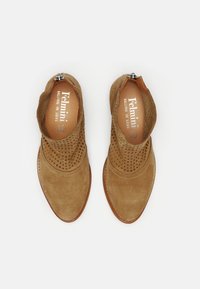 Bottines en suède marron avec un design perforé sur le dessus, bout pointu et fermeture éclair latérale. Doublure intérieure en cuir lisse.