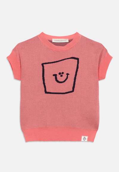 Pull en tricot rose à manches courtes avec un carré noir délimité et un motif de visage souriant sur le devant, ainsi qu'une petite étiquette blanche de la marque à l'ourlet.