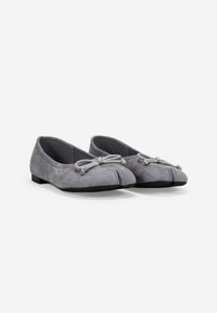 Un paio di ballerine in suede grigio con design a punta divisa e piccolo fiocco decorativo sulla parte superiore, posizionate affiancate su uno sfondo bianco.