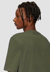 Olijfgroene t-shirt met korte mouwen, een ronde hals en een zachte textuur, met een relaxed fit en eenvoudig ontwerp.