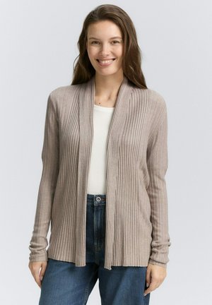 Beige ribgebreide cardigan met een open voorkant, lange mouwen en een zachte textuur, gecombineerd met een witte top en donkerblauwe jeans.