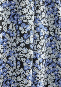 Tissu noir avec un motif dense de petites fleurs blanches et bleu clair créant un design floral texturé.