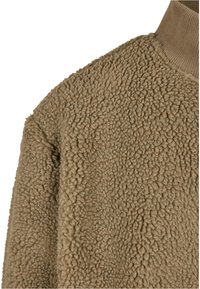Tan fleece jas met een getextureerd, pluizig oppervlak en een geribbelde kraag. Heeft een losse pasvorm en minimale stikseldetails.