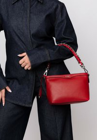 Red leather handbag with a braided red and silver chain strap; smooth texture, rectangular shape, silver hardware accents.