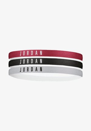 Three stretch bands in red, black, and white featuring "JORDAN" in bold black lettering. Made of textile material with a smooth texture.