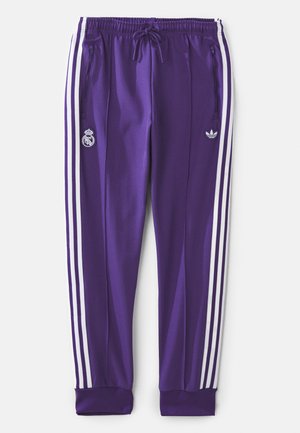 Purple athletic pants with white side stripes, elastic waistband, drawstring, zippered pockets, and two logos: Real Madrid and Adidas.