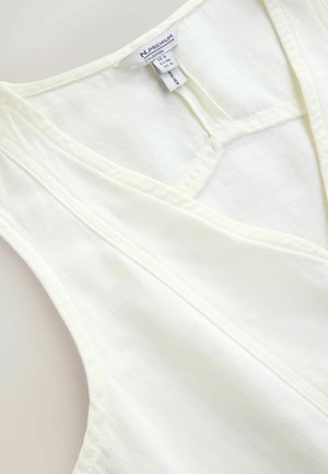 White sleeveless V-neck garment with visible stitching and a size label showing UK 8, EU 36, and US S.