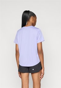 Lavendli niiskust imav spordipluus lühikeste varrukatega ja ümmarguse kaelusega, koos mustade lühikesed pükstega, millel on valge täpikujuline hekk.