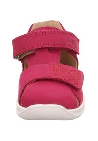 Rosa Kindersandale mit einem einzelnen Klettverschluss, dekorativer Schmetterlingsprägung und weißer Gummisohle. Hergestellt aus weichem Leder.